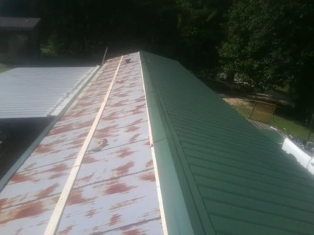 Old rusted panels beside newly installed green metal roofing — Wind Damage Roof Repair by Roofing Brothers in Prinsburg