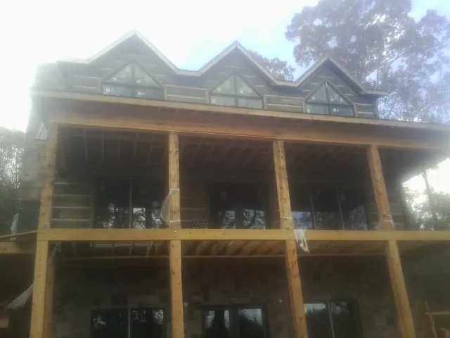 Dormers and porch framing on a large log home under construction — Roof Coating work by our crew in Prinsburg