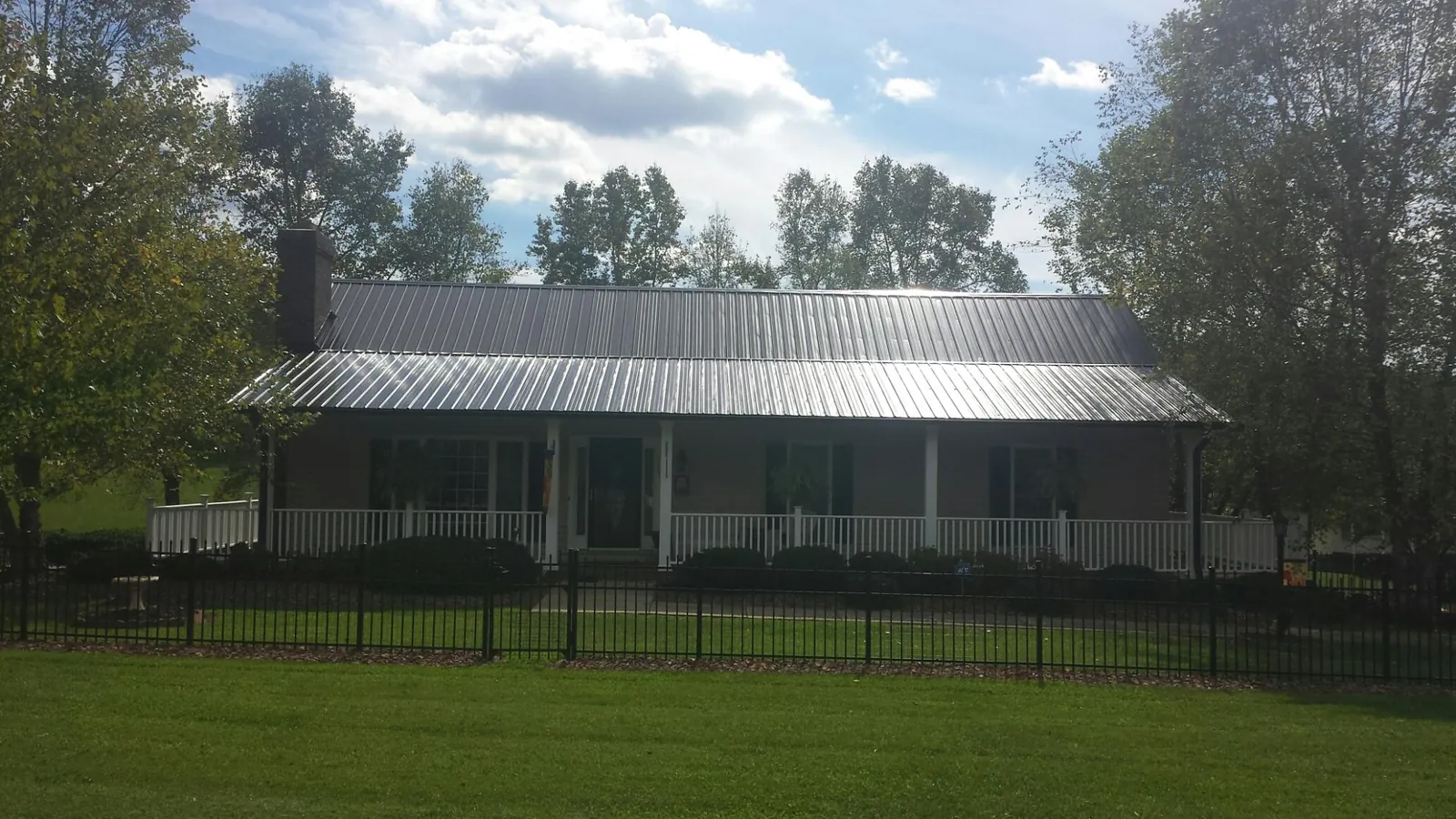 Gray metal roof on a brick ranch with a full width front porch — Gutter Guard Installation work by our crew in Prinsburg