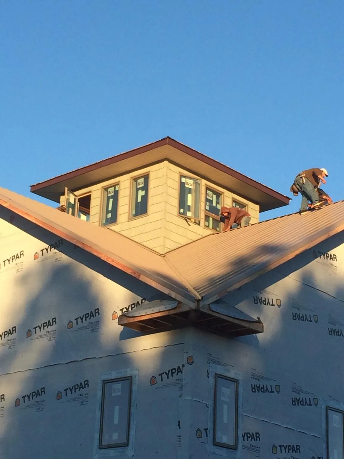 Roofers working around a rooftop cupola on a new metal roof at sunset — Roof Waterproofing in Prinsburg by Roofing Brothers
